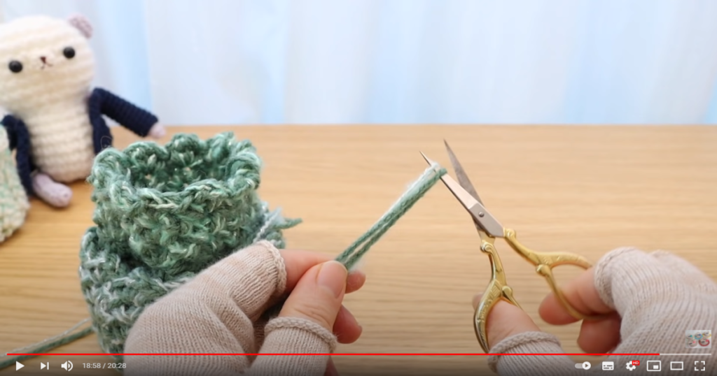 糸始末するために編み終わりから毛糸を数センチ残し、ハサミを使ってカットしている様子の画像