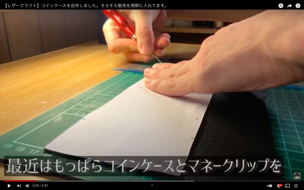 型紙を使ってレザーをカットしているところ。
「最近はもっぱらコインケースとマネークリップを」のテロップが表示されている。