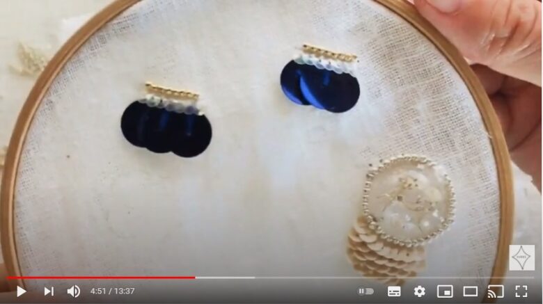 刺繍枠の生地に、大きめの紺色のスパンコールを使ったパーツが2つと、樹脂を使ったパーツ1つの完成品を映す写真。