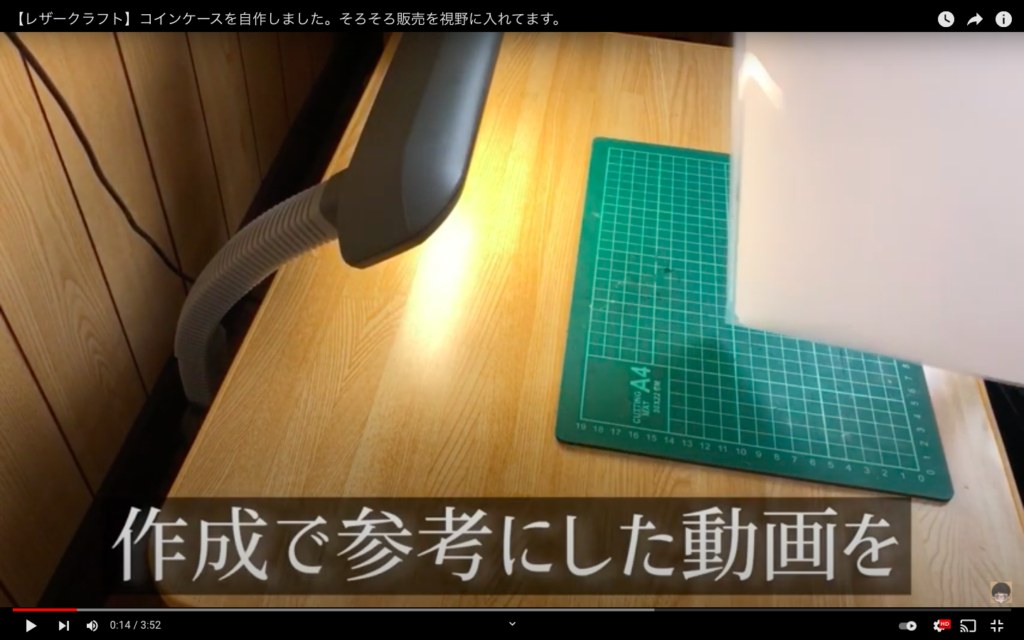 机にカッターマットが置かれていて、画面右端に白い紙が映っている。
「作成で参考した動画を」のテロップが表示されている。