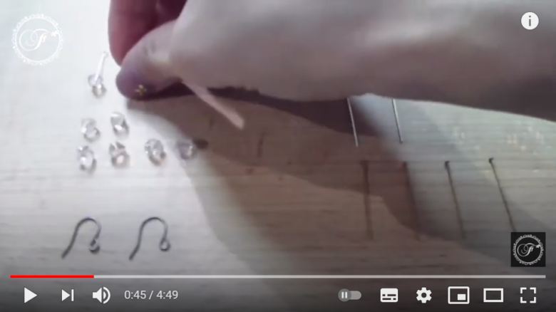 投稿者がピアスに使うビーズを摘まんでいる場面。動画では、ピアノのBGMが流れている。
