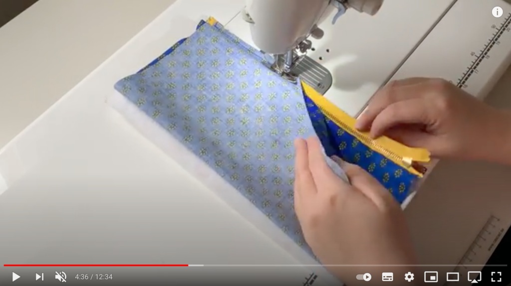 布を折りたたんで、端をミシンで縫っている様子。