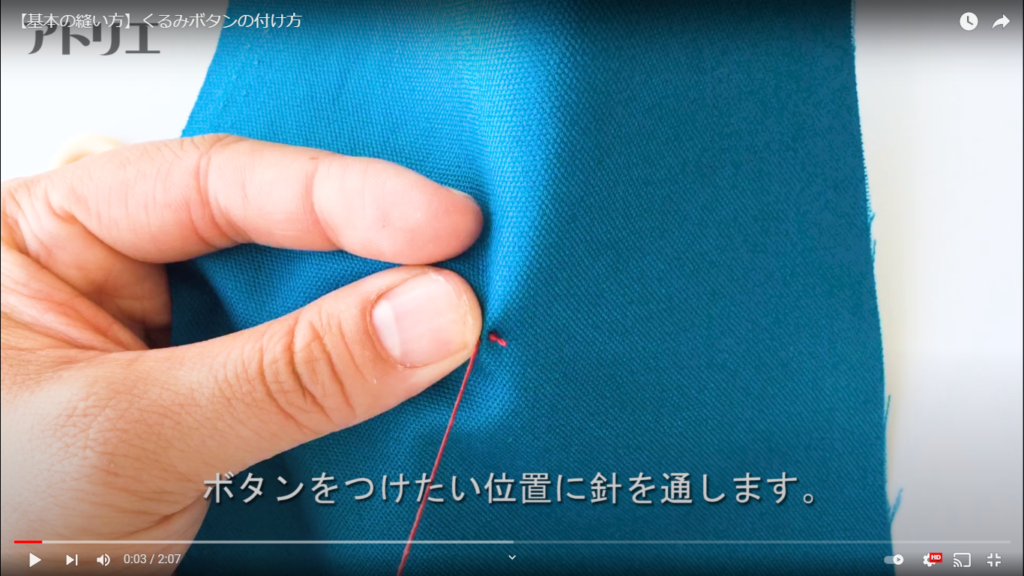 玉結びをして、ボタンを付けたい位置に針を通している様子を拡大したシーン。