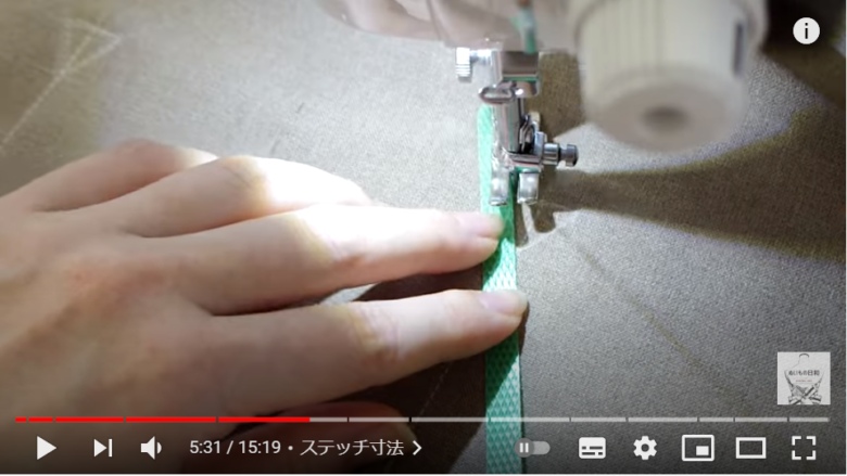 ミシンでポケット部分を縫っている場面。縫いやすいように、身近なあるアイテムが針の傍に当てられているのが分かる。