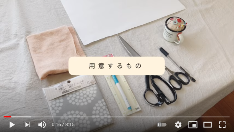 用意する材料や道具一式を紹介している場面。無地の裏布と柄入りの表布、チャコペン、裁ちばさみなどがキレイに並べられている。