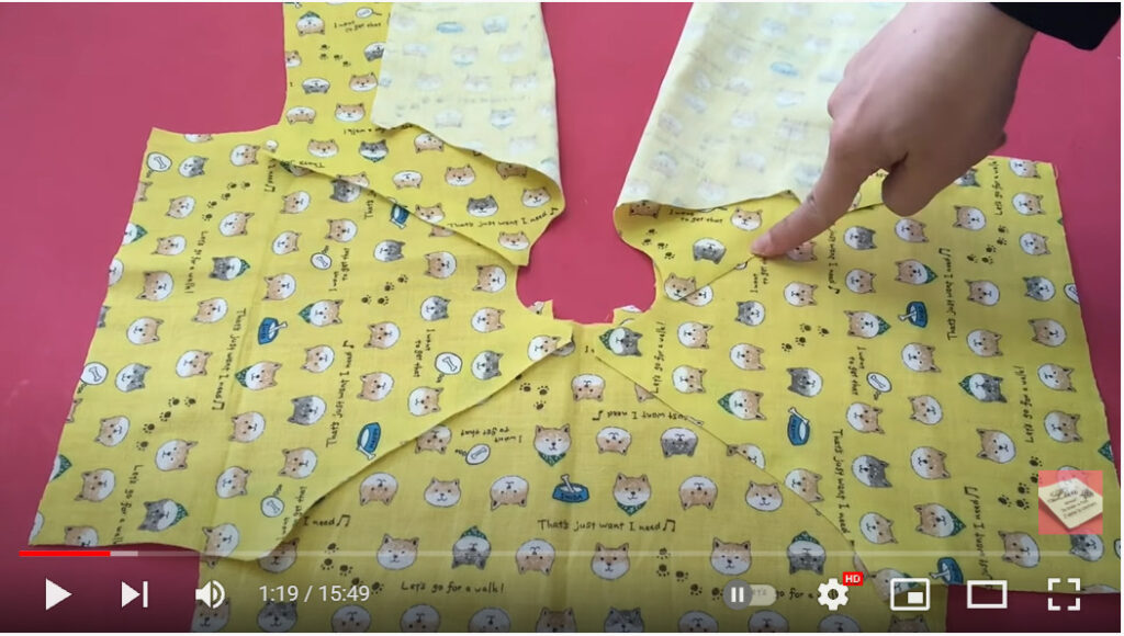 パーツをどう縫い合わせるか、指で示している写真です。黄色地に小さな柴犬の可愛い柄の布地です。