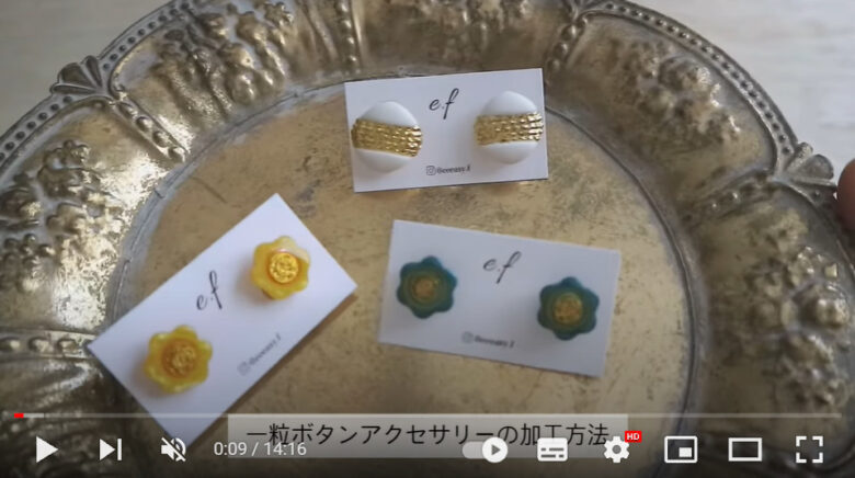 ボタンを加工して作られたピアス3種類がゴールドのトレイに乗っている。ピアスに加工されたのは黄色と緑のお花の形のボタンと、白にゴールドが入った丸い形のボタンだ。