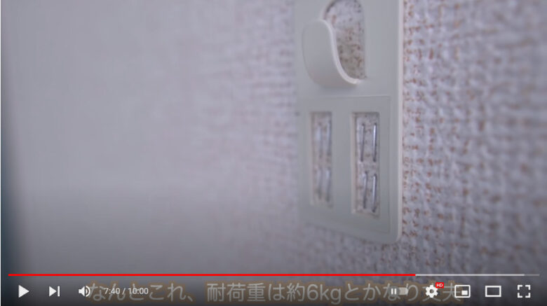 ホッチキスで止めるタイプの壁掛けフックが白い壁に固定されている様子