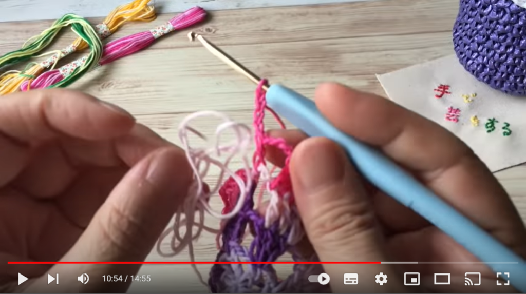 3段目の途中から4段目をピンク色に糸を変えてかぎ針で編んでいます。これから編む糸がからまっています。