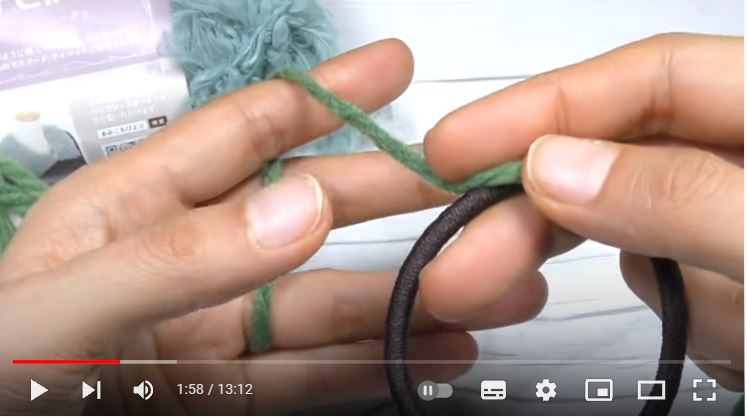 黒いヘアゴムにモスグリーンの毛糸を巻き付けるところの画像