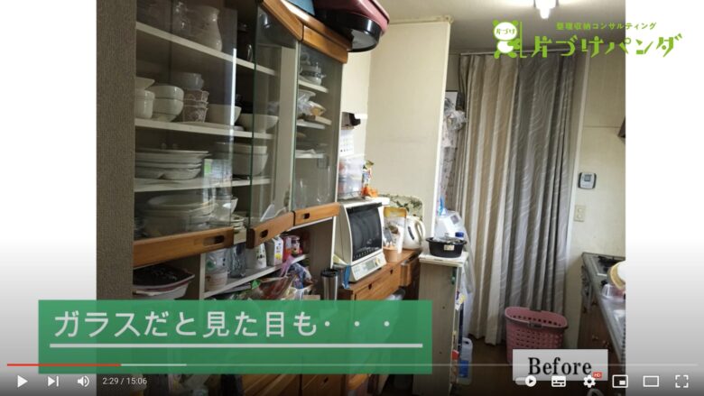 食器棚を片付ける前の状態の写真です。ガラス扉の食器棚の中にたくさんの食器や食材が入れられています。