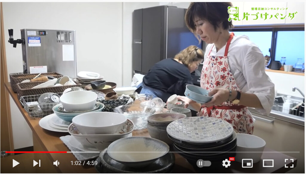 中村さんと相談者の方がキッチンの中の食器をテーブルに出している写真です。たくさんの種類の食器が積み重なり、置ける場所はもうなさそうです。