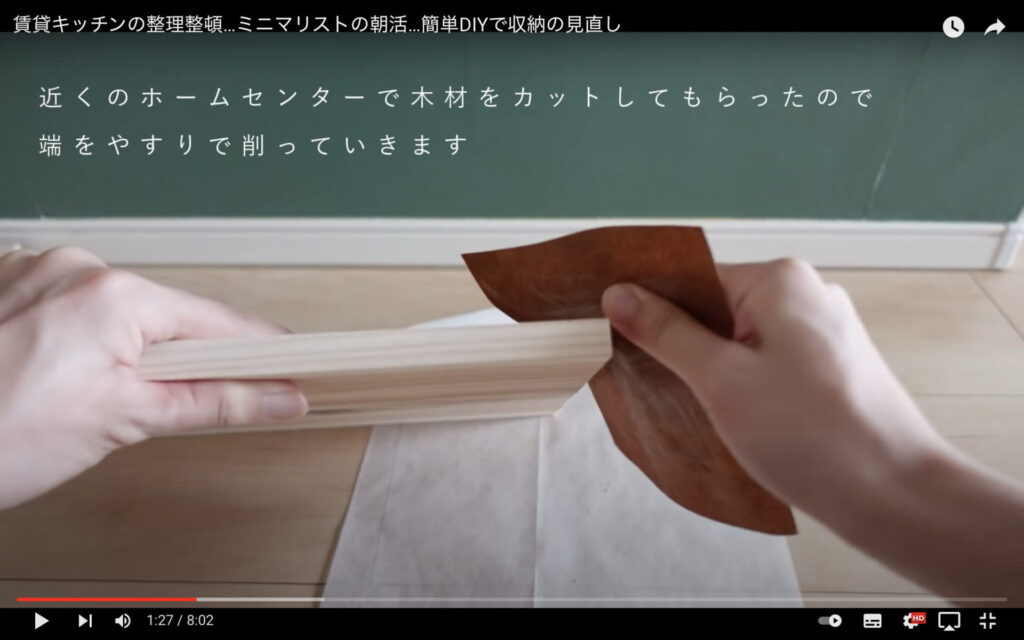 maiが収納棚DIYに使用する木材を、紙ヤスリで削っている様子を映した画像。