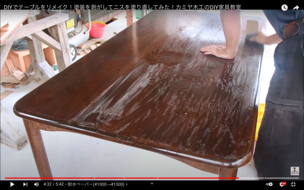 ニスを塗ったテーブルにやすりをかけている表面に艶を出している画像です。