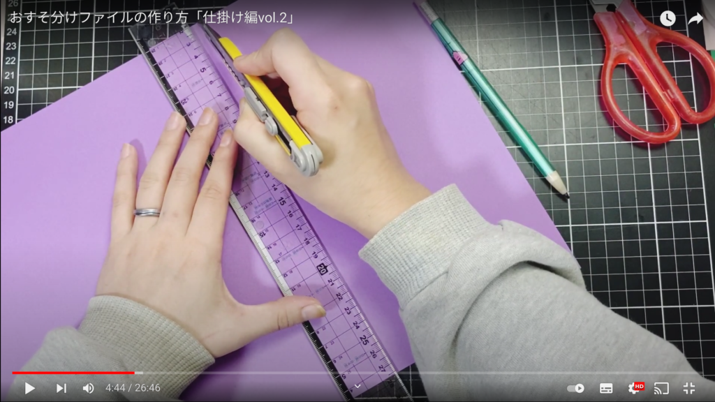 定規とカッターを使って紫色の紙を切るところ