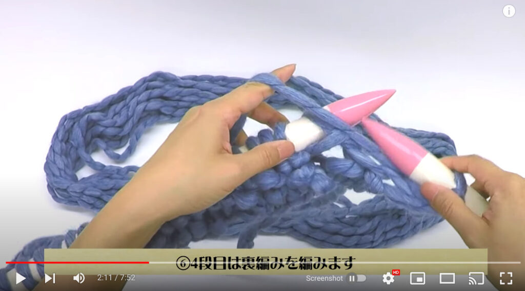 編み棒を使って、4段目を裏編みで編んでいる写真。