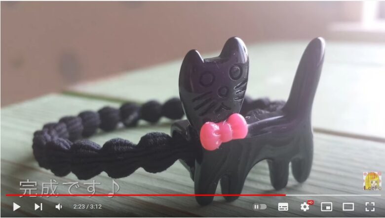 ピンクリボンをつけた黒猫パーツがついた、黒色のヘアゴムの画像
