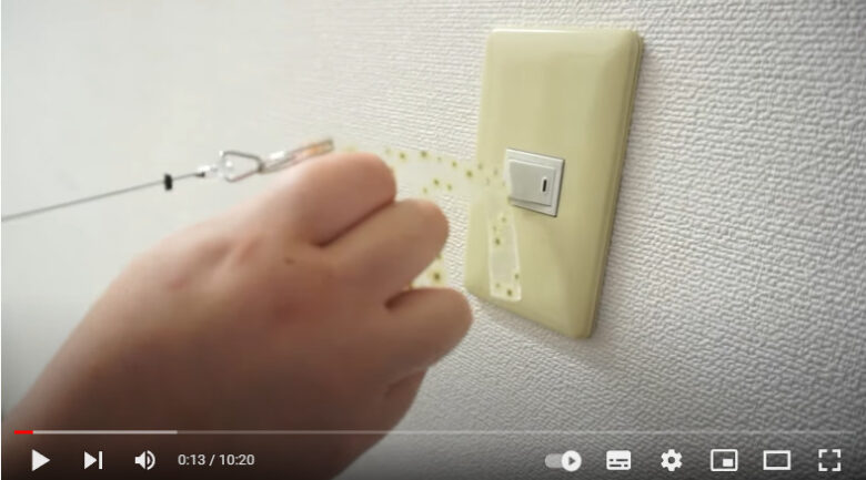 サンシャインさんが自分で作ったプラ板のドアオープナーを使って、電気のスイッチを入れている画像です。
花柄のかわいいドアオープナーです。