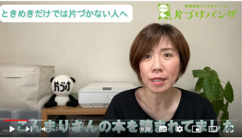 こちらに語りかけている中村さんの写真です。中村さんは、すっきりとしたショートボブの髪型が印象的な女性です。後ろには顔に「片づけ」と書かれたパンダの編みぐるみが置かれています。