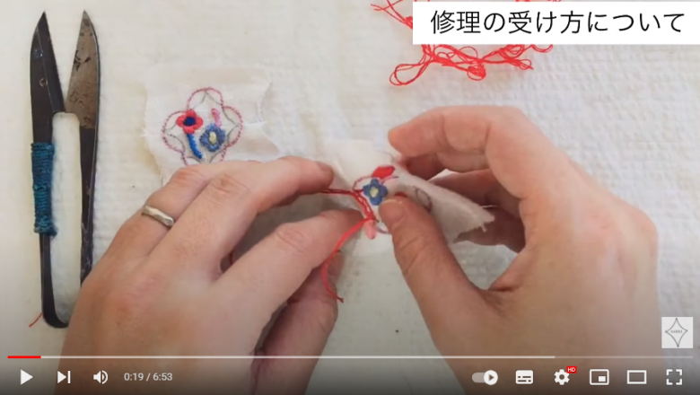 nakkiさんが刺繍をしている様子。赤い糸で白い布に刺繍をしています。
