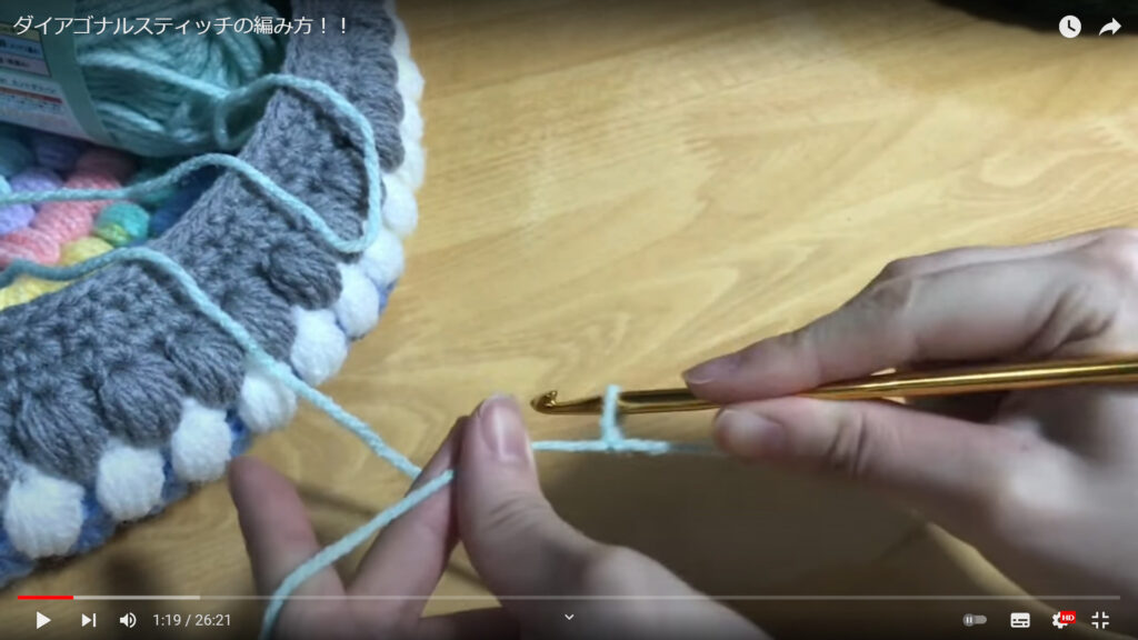 左手に毛糸、右手にかぎ針を持って編み始めようとしています。