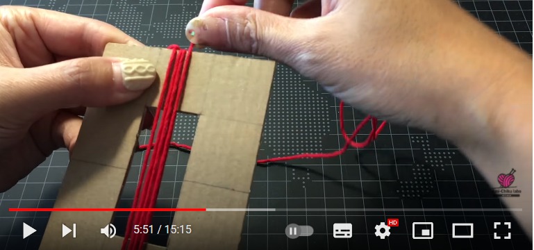 段ボール板に赤い糸を巻きつけて、タッセルを作っている段階です。