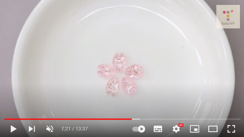 白い皿の上に乗った、レジンで作った5枚の小さなさくらの花弁が画面に映っている。