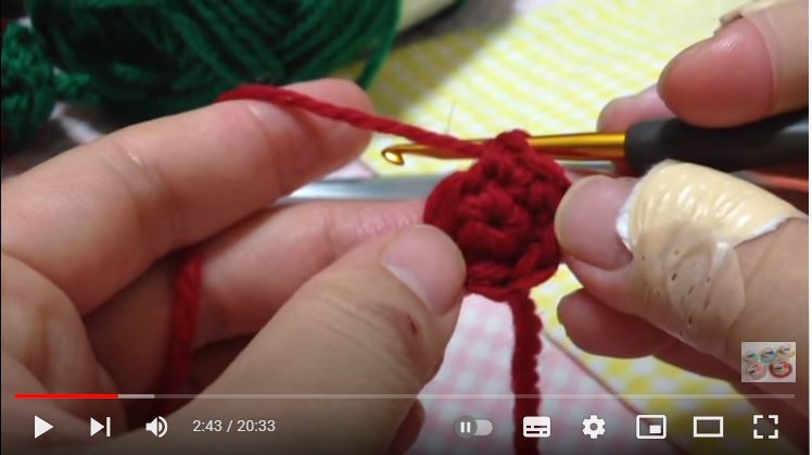 かぎ針で赤い毛糸の円の二段目を編んでいるところ