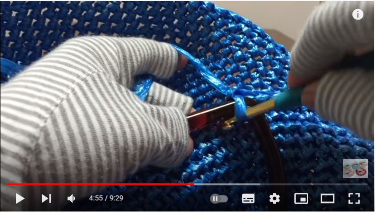 水色のビニールテープバッグに茶色のクリアカラーの取っ手をかぎ針で編みつけているところの画像