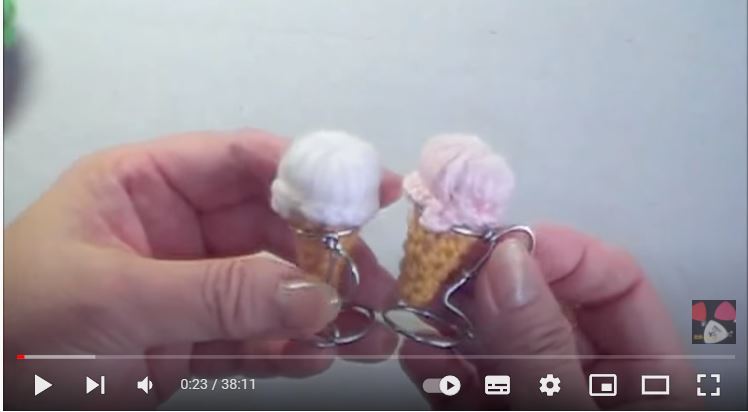 毛糸で編んだ白色と薄ピンクのアイスクリームを一つずつ持って見せている画像