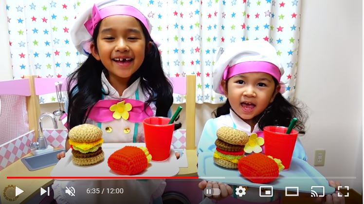 お店屋さんごっこの衣装を着てハンバーガー、フライドポテト、ドリンクのカップをトレーに乗せて立っている女の子二人の画像