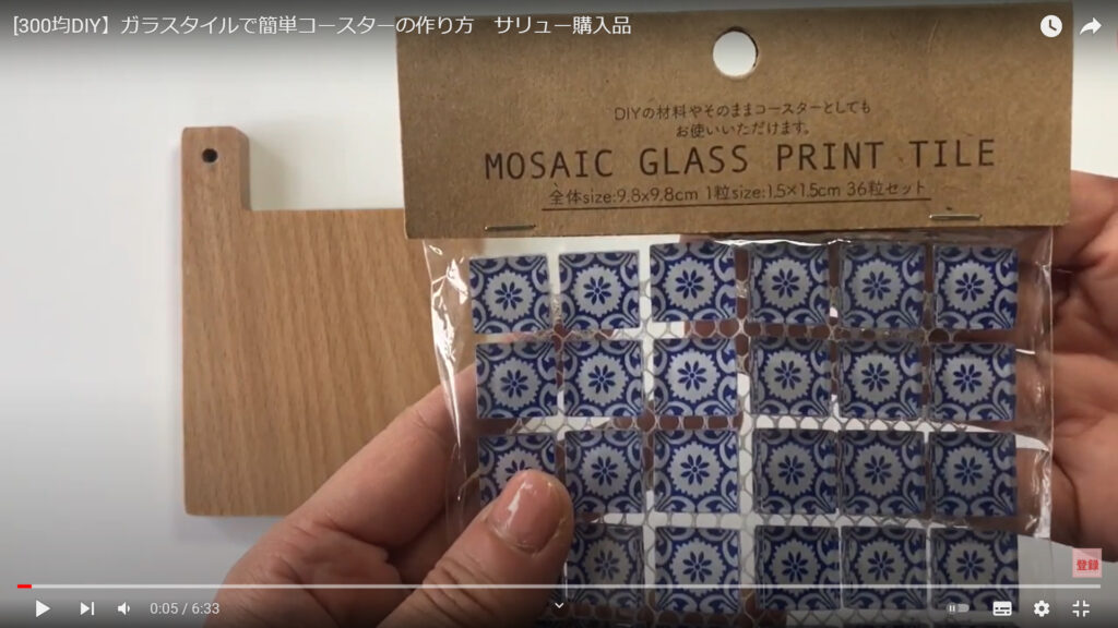 ガラスタイルで作るコースターの材料を紹介している動画で、土台となる木のコースターと袋に入ったガラスタイルを手に持った画像。