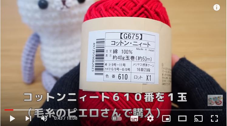 赤色のコットン糸の品質表示を見せている画像　背景に白いくまの編みぐるみ