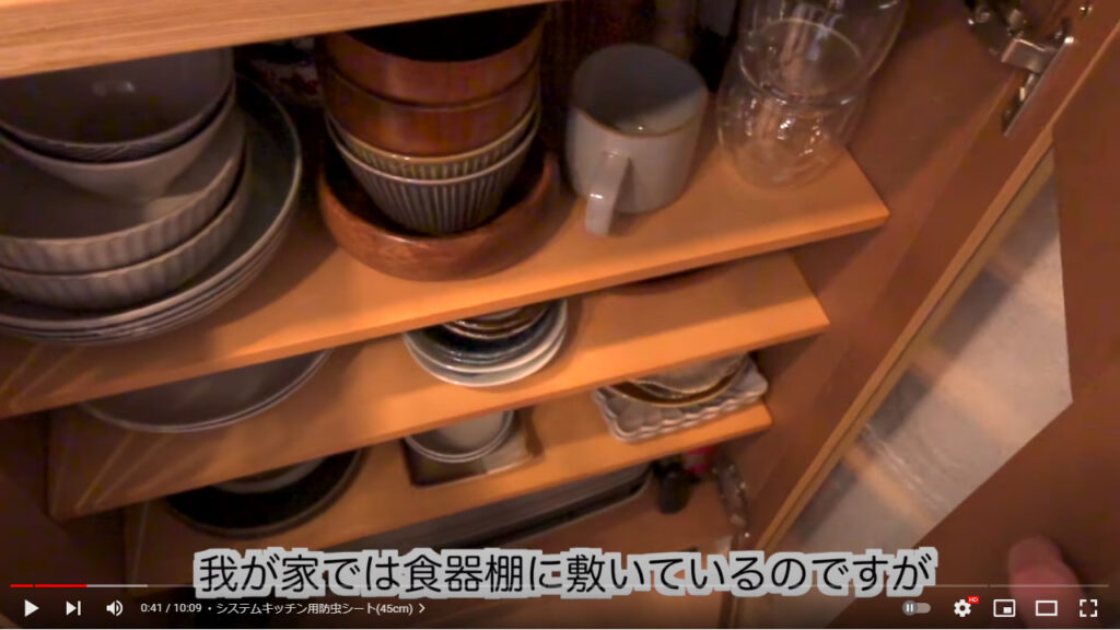 画像は自宅の食器棚を映している様子です。食器の下にニトリの防虫シートが敷かれています。
下の字幕には「我が家では食器棚に敷いているのですが」と書かれています。