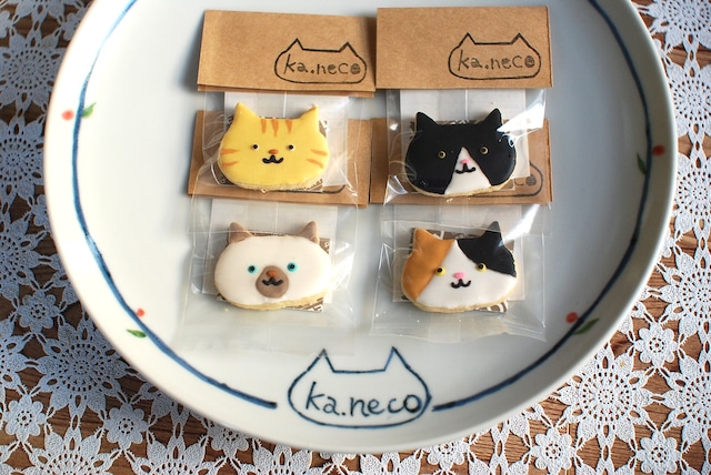 4種類の猫の柄をしたアイシングクッキーが皿の上に乗せられている写真。