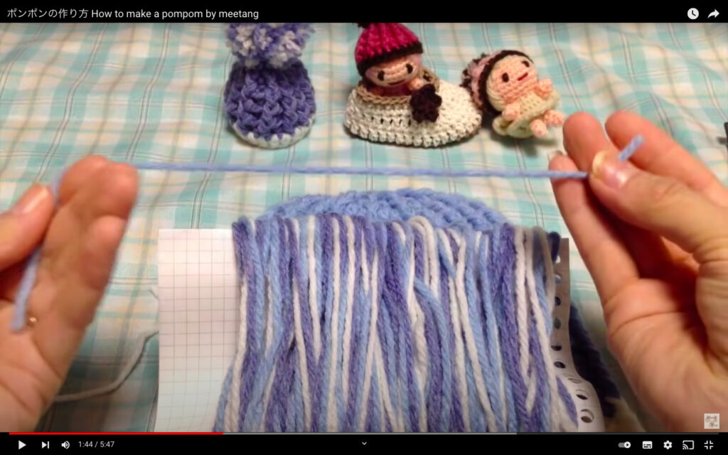 ルーズリーフに巻き付けられている毛糸と、水色の毛糸を1本手に持っているところが写っている様子。