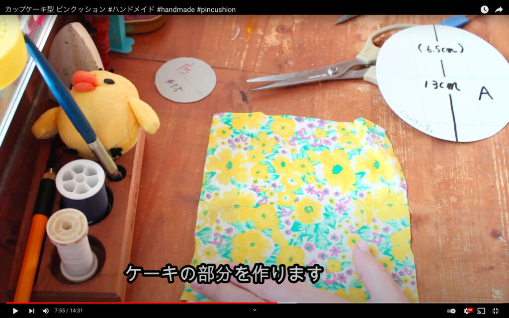 花柄の布と、丸い型紙。「ケーキの部分を作ります」のテロップが表示されている。