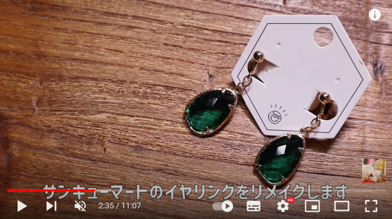 サンキューマートの購入品のイヤリングが机に乗っている。リメイク前は緑色の宝石のようなパーツがついているだけのシンプルなもの。