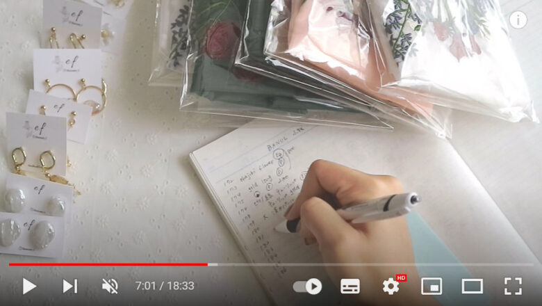 机の上にはアクセサリーの他に、花の刺繡が入ったエコバッグも乗っている。こちらもノートに品番と特徴を記載していく。