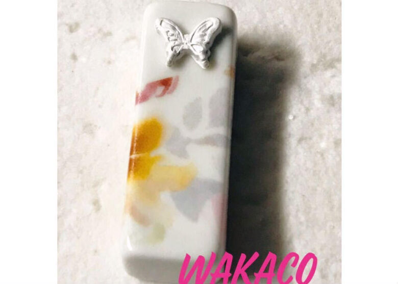 「磁器　蝶の箸置き　シルバー」という商品の写真。シルバーの蝶が磁器の箸置きの上部に飾られている。