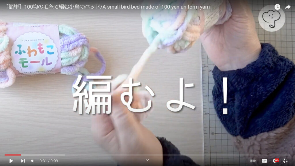 小鳥のベッドの作り方でモール毛糸で編んでいく作業を説明した動画の途中で、手で毛糸を出し、「編むよ」という文字が表示されている画像。

