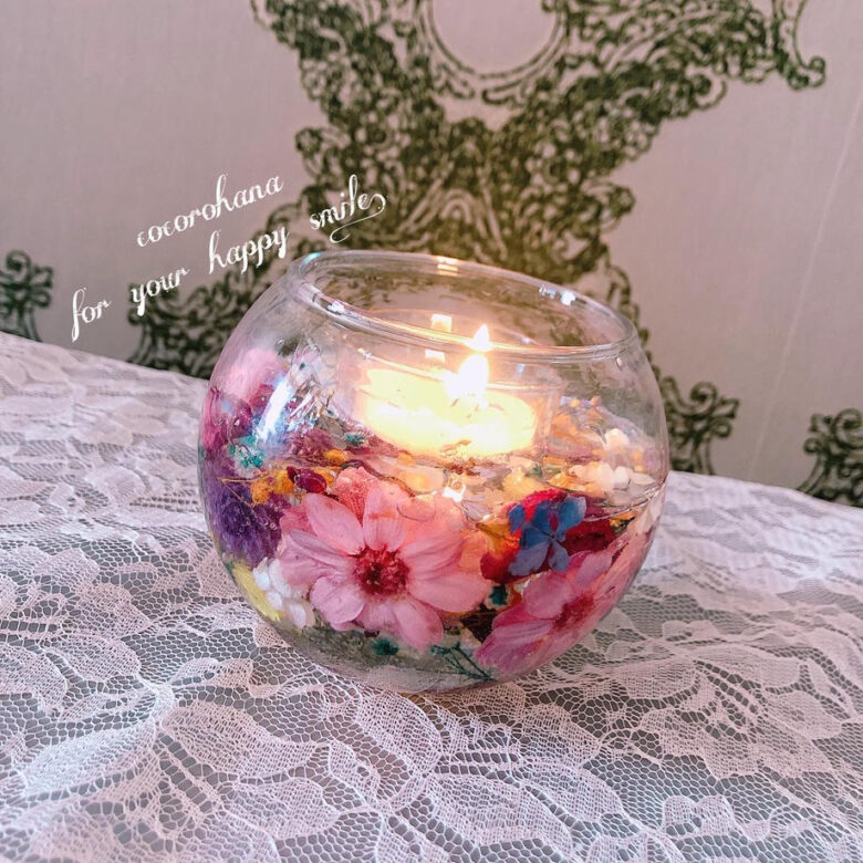 「Candle Glass Flower」という商品の写真。周りはお花があしらわれていて中央部分にキャンドルが置かれている。