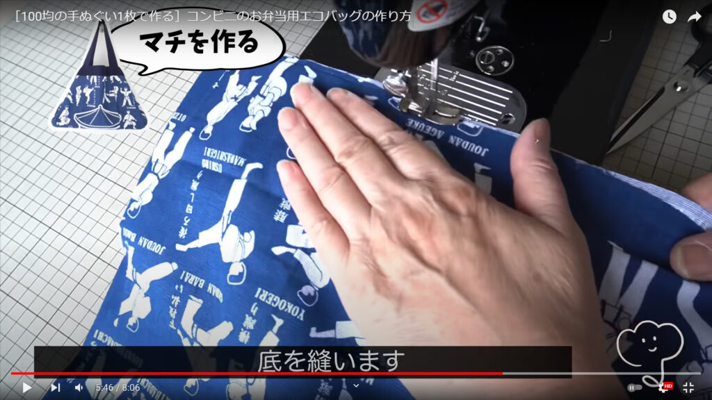 エコバッグのマチを作る作業を解説している動画で、ミシンで底の部分を縫っている様子と共に「底を縫います」という文が表示された画像。