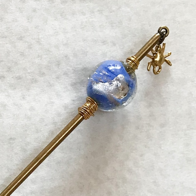 クモのチャームが付けられたゴールドのかんざしです。飾り部分には青とシルバーのトンボ玉が付けられています。
