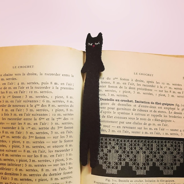 読みかけの本の見開きに、黒猫のしおりが横たわっています。猫がのびてぬむっているようです。
