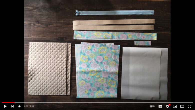 今回使用する材料がきれいに並べられています。表布は、ベース色がターコイズブルーで、ピンクと黄色の花柄です。持ち手用布も同じ生地を使用しています。内布とアクリルテープはベージュ色です。