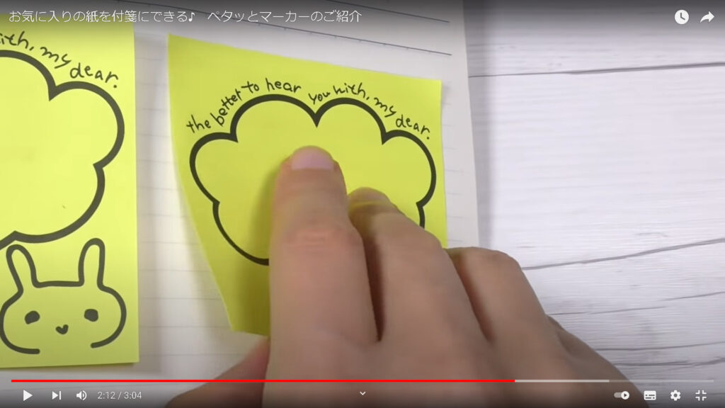 ペンを使って付箋に変身させた、黄色いメモ用紙を、ノートにはりつけている様子です。
