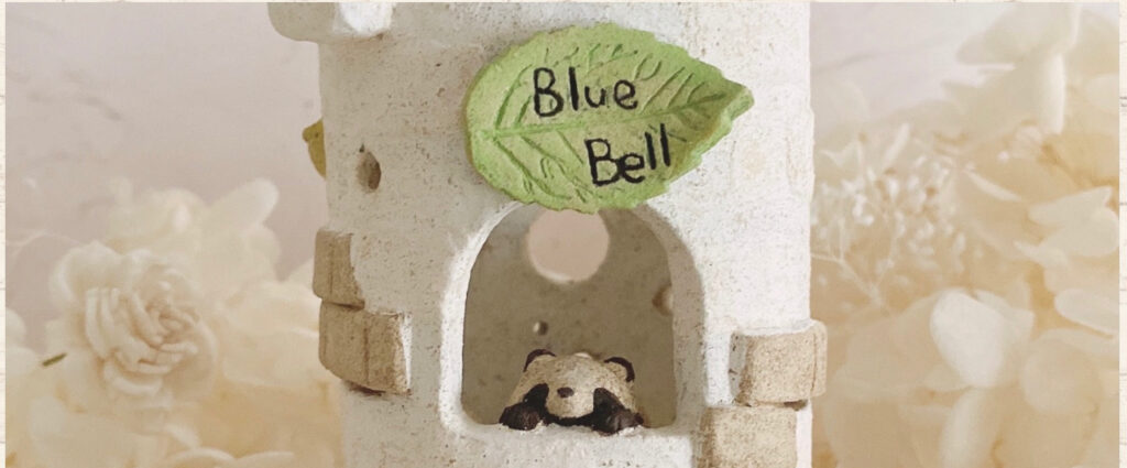 村井梨乃さんが運営するネットショップ「BlueBell」のトップ画像です。たぬきが小窓から顔をのぞかせています。