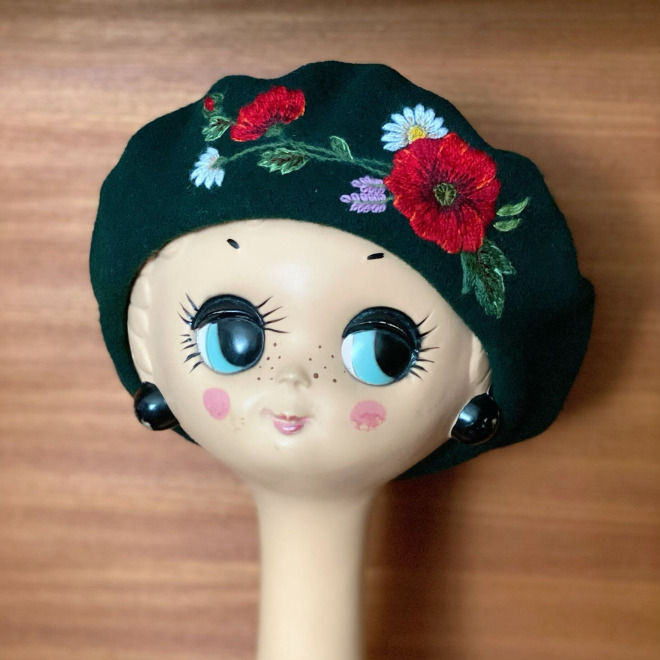 画像は商品を映している様子です。
女の子の人形の頭に商品のベレー帽が被せられています。
ベレー帽の正面に刺繡が来るように被せられています。