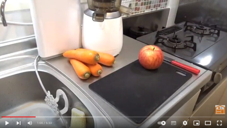 キッチンを背景に今回作るジュースの人参とりんごとジューサーの画像